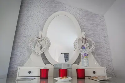 a dressing table with two mirrors and red candles at The Leicester in Southport
