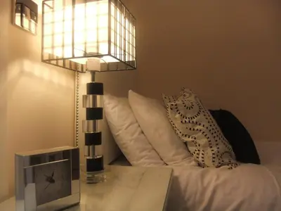 a bed with white pillows and a table with a lamp at The Leicester in Southport