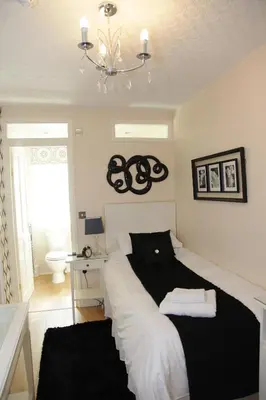 a bedroom with a black and white bed and a chandelier at The Leicester in Southport