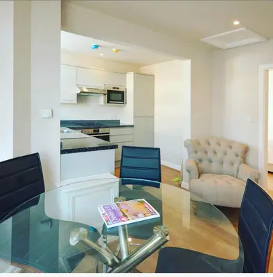 a living room with a glass table and blue chairs at Stay in Blackpool