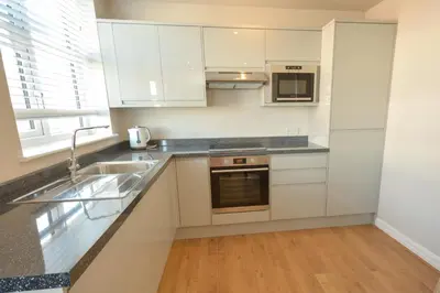 a kitchen with white cabinets and a sink at Stay in Blackpool