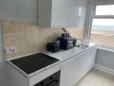 a white kitchen with a sink and a microwave at The Clarendon Hotel in Morecambe