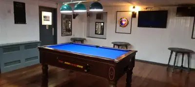 a pool table in a room with two stools at The Clarendon Hotel in Morecambe