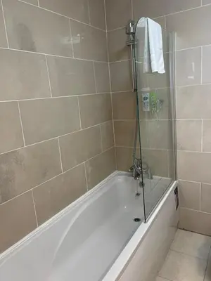 a bathroom with a bath tub with a shower at The Clarendon Hotel in Morecambe