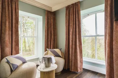 a living room with a chair and two windows at Grange Hotel in Grange Over Sands