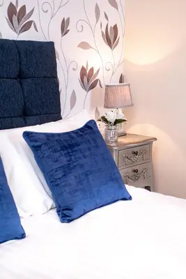 a bed with blue pillows and a table with a lamp at MARS Hotel Seaview Blackpool in Blackpool