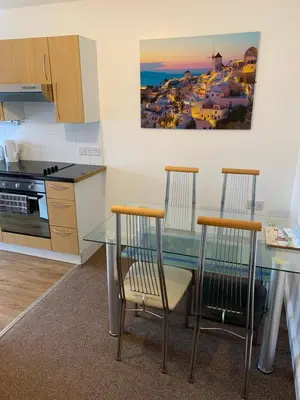 a kitchen with a glass table and two chairs at delamere holiday apartments in Blackpool