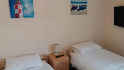 two beds in a room with a lighthouse on the wall at delamere holiday apartments in Blackpool