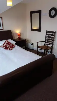 a bedroom with a bed and a chair and a mirror at delamere holiday apartments in Blackpool