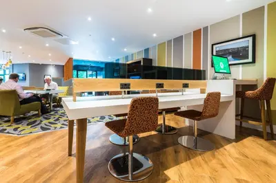 a lobby with a table and chairs and people sitting at tables at Holiday Inn Lancaster by IHG in Lancaster