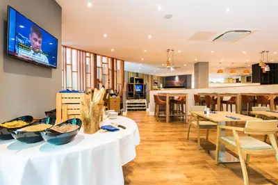 a dining room with tables and a tv on the wall at Holiday Inn Lancaster by IHG in Lancaster