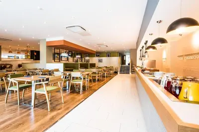 a restaurant with tables and chairs and a counter at Holiday Inn Lancaster by IHG in Lancaster