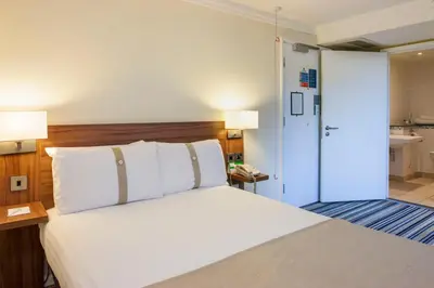 a bedroom with a large bed and a bathroom at Holiday Inn Lancaster by IHG in Lancaster