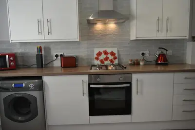a kitchen with white cabinets and a stove and a dishwasher at Adelaide Apartments in Blackpool