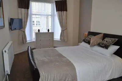 a bedroom with a large bed with two faces on the pillows at Adelaide Apartments in Blackpool