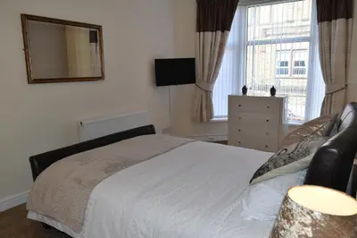 a bedroom with a bed and a mirror on the wall at Adelaide Apartments in Blackpool
