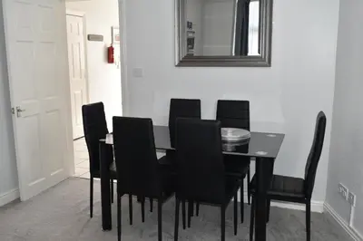 a black dining room table with black chairs and a mirror at Adelaide Apartments in Blackpool