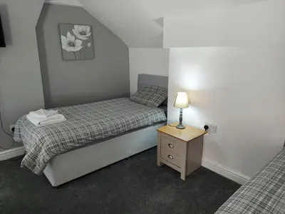 two twin beds in a small room with a night stand at Ambrose Hotel in Barrow in Furness