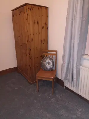 a room with a chair and a wooden cabinet at Ambrose Hotel in Barrow in Furness