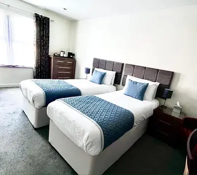 a hotel room with two beds with blue pillows at Mode Hotel St Annes in Lytham St Annes