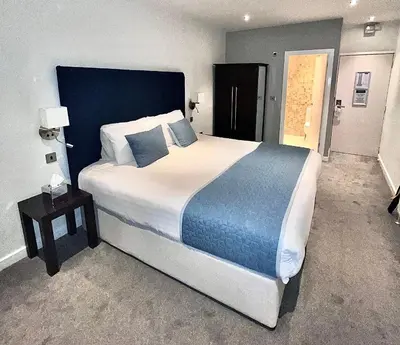 a bedroom with a large bed with a blue headboard at Mode Hotel St Annes in Lytham St Annes
