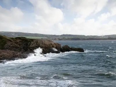 a rocky shoreline with waves crashing on the water at Tranquillity in Millom