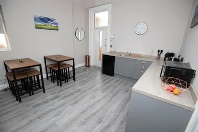 a kitchen with chairs and tables and a clock on the wall at Lynwood House in Southport