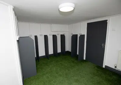 a room with a row of changing stalls with green grass at Lynwood House in Southport
