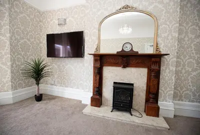 a living room with a fireplace and a mirror at Lynwood House in Southport
