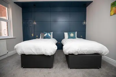 two beds in a room with blue walls at Lynwood House in Southport