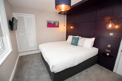 a small bedroom with a bed with white sheets at Lynwood House in Southport