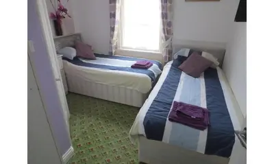 two beds in a small room with a window at The Salendine in Blackpool