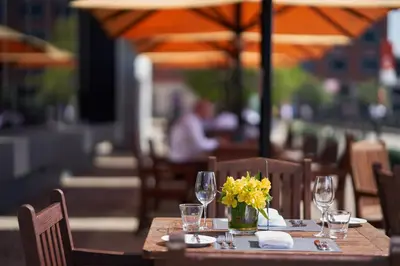 a wooden table with glasses and a vase of yellow flowers at Malmaison Liverpool in Liverpool