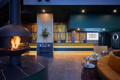 a lobby with a fireplace and a couch and tables at Malmaison Liverpool in Liverpool