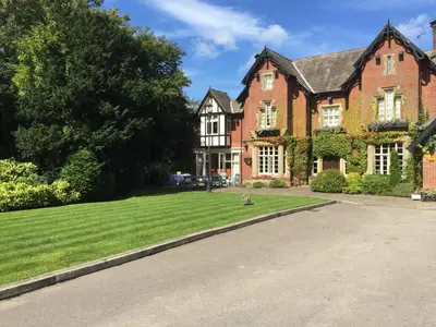 a brick house with a dog sitting on the grass at The Villa Country House Hotel in Wrea Green