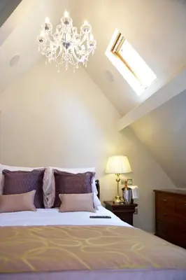 a bedroom with a large bed with a chandelier at The Villa Country House Hotel in Wrea Green