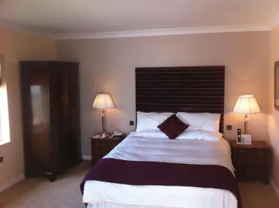 a bedroom with a large bed with two lamps at The Villa Country House Hotel in Wrea Green