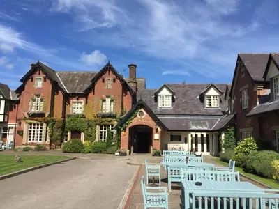 a large brick building with white chairs in front of it at The Villa Country House Hotel in Wrea Green