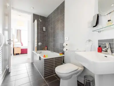 a bathroom with a toilet and a sink and a tub at PREMIER SUITES Liverpool in Liverpool