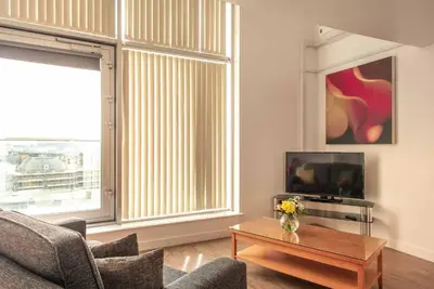 a living room with a couch and a tv and a table at PREMIER SUITES Liverpool in Liverpool