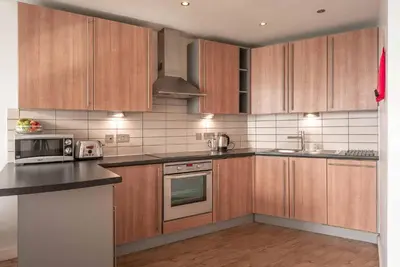 a kitchen with wooden cabinets and a stove top oven at PREMIER SUITES Liverpool in Liverpool