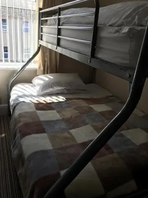 a bunk bed with a checkered blanket on it at Glenheath Hotel in Blackpool