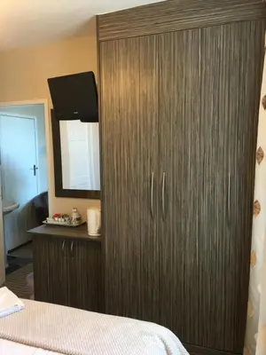 a bedroom with a large wooden cabinet with a mirror at Glenheath Hotel in Blackpool