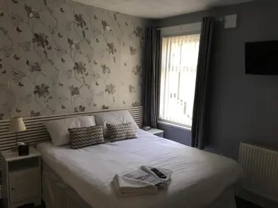 a bedroom with a white bed with a window at Glenheath Hotel in Blackpool
