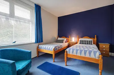 a bedroom with two beds and a chair at Lancaster Townhouse in Lancaster