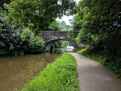 a stone bridge over a river with a path at Lancaster Townhouse in Lancaster