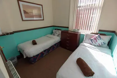 a small room with two beds and a window at The Riviera Hotel in Blackpool