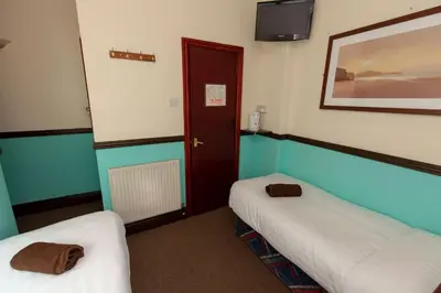 a room with two beds and a red door at The Riviera Hotel in Blackpool