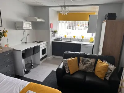 a living room with a couch and a kitchen at Berkswell Holiday Apartments in Blackpool