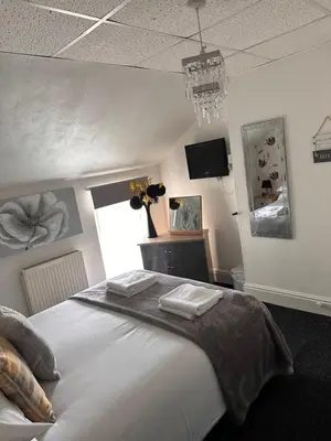 a bedroom with a large white bed and a tv at Berkswell Holiday Apartments in Blackpool